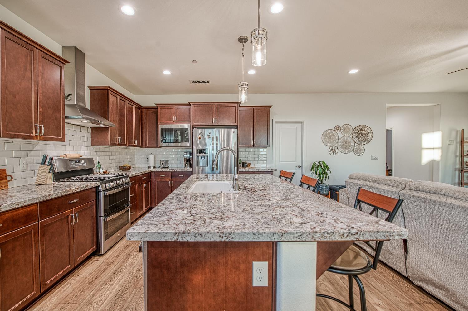 4534 Hillside Road Madera, CA 93636 - Photo 41 of 92 a kitchen with kitchen island granite countertop wooden cabinets and a refrigerator