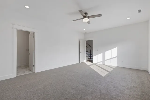 an empty room with windows and ceiling fan