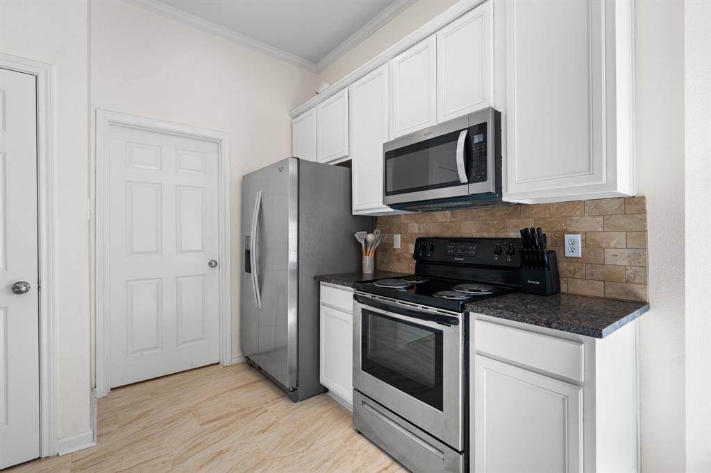 7 St Charles Place Midlothian, TX 76065 - Photo 11 of 27 a kitchen with stainless steel appliances white cabinets a stove a microwave and a refrigerator