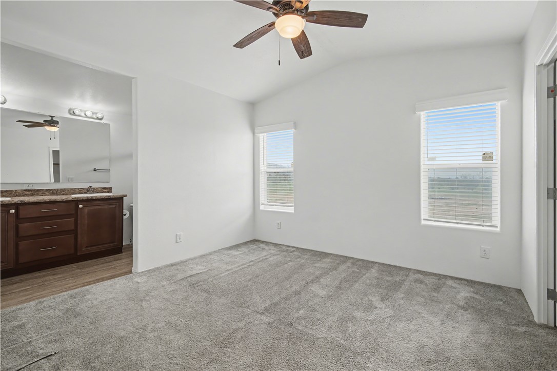 3058 West Carmichael Road Golden Valley, AZ 86413 - Photo 12 of 36 Unfurnished bedroom featuring vaulted ceiling, a ceiling fan, dark colored carpet, and connected bathroom