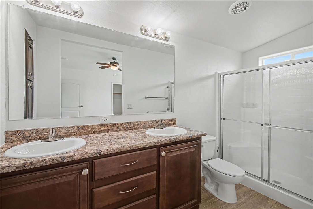 3058 West Carmichael Road Golden Valley, AZ 86413 - Photo 15 of 36 Full bath featuring double vanity, a shower stall, light wood-style floors, and a ceiling fan