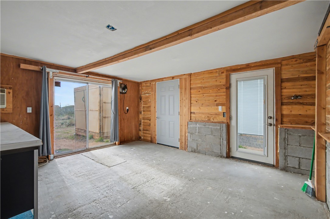 3058 West Carmichael Road Golden Valley, AZ 86413 - Photo 18 of 36 Unfurnished living room featuring wooden walls and beam ceiling