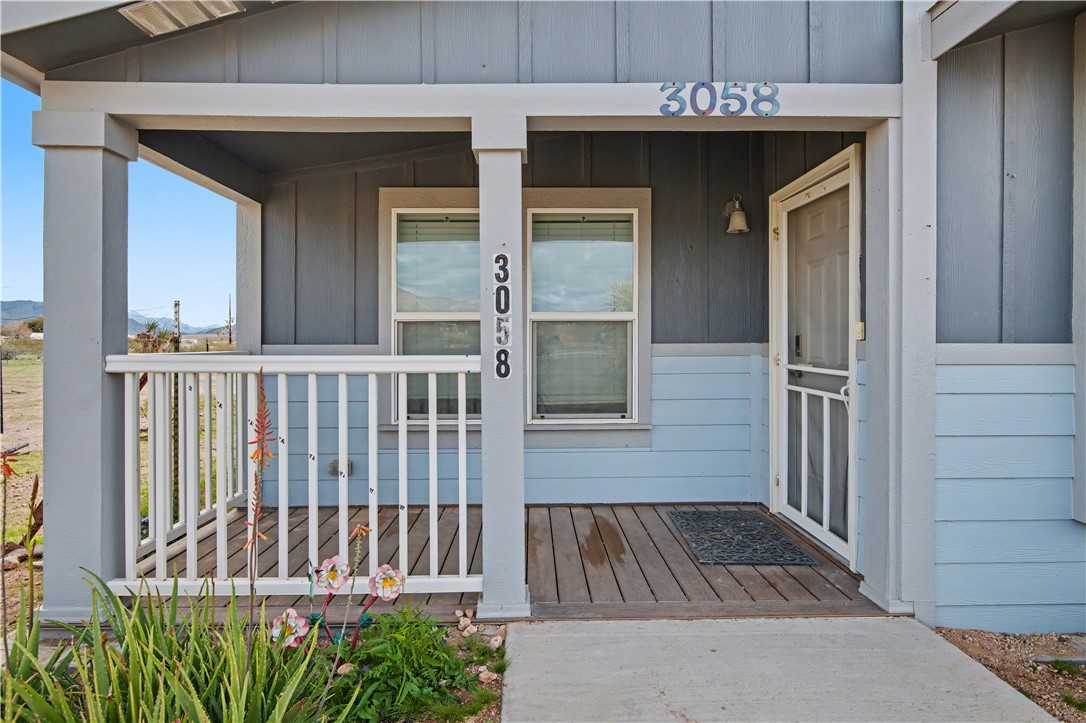 3058 West Carmichael Road Golden Valley, AZ 86413 - Photo 2 of 36 Doorway to property featuring a porch and board and batten siding