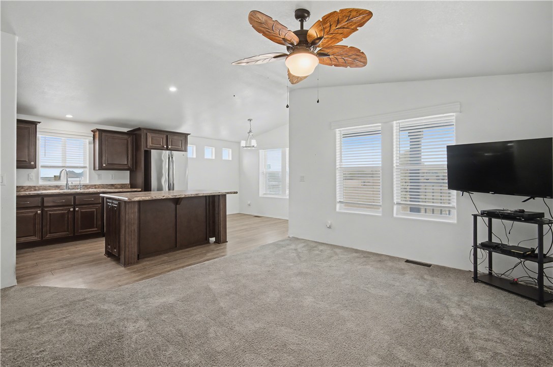 3058 West Carmichael Road Golden Valley, AZ 86413 - Photo 4 of 36 Kitchen featuring dark brown cabinets, a kitchen island, vaulted ceiling, freestanding refrigerator, and a ceiling fan