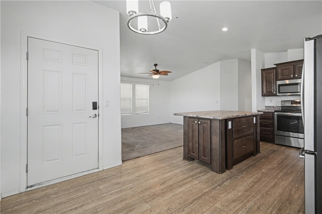 3058 West Carmichael Road Golden Valley, AZ 86413 - Photo 36 of 36 Kitchen featuring dark brown cabinets, stainless steel appliances, open floor plan, decorative light fixtures, and a kitchen island