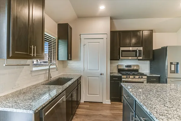 a kitchen with stainless steel appliances granite countertop a sink stove microwave and refrigerator