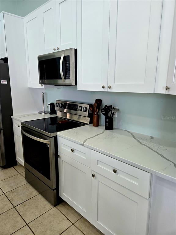7838 Trail Run Loop New Port Richey, FL 34653 - Photo 13 of 36 a kitchen with white cabinets and black appliances