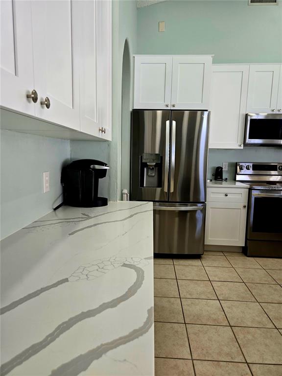 7838 Trail Run Loop New Port Richey, FL 34653 - Photo 14 of 36 a kitchen with a refrigerator a stove a microwave and cabinets