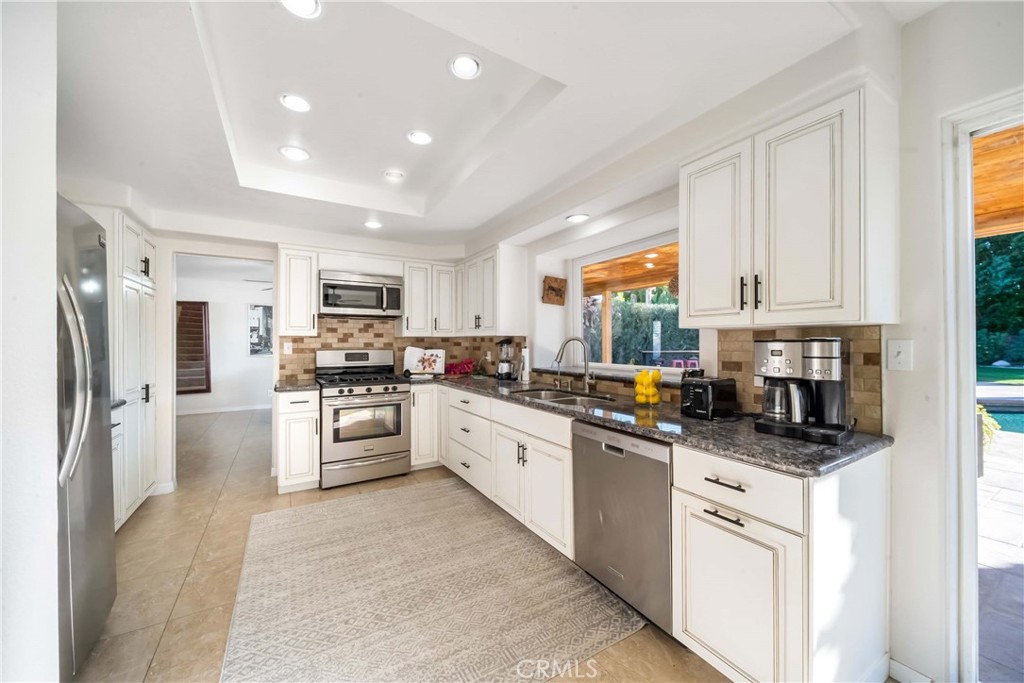 68845 Durango Road Cathedral City, CA 92234 - Photo 18 of 75 a kitchen with stainless steel appliances granite countertop a refrigerator a sink dishwasher a stove and white cabinets with wooden floor