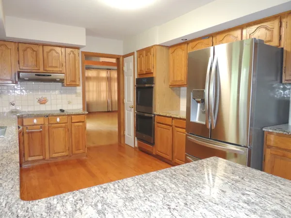a kitchen with kitchen island granite countertop wooden cabinets a refrigerator and a sink