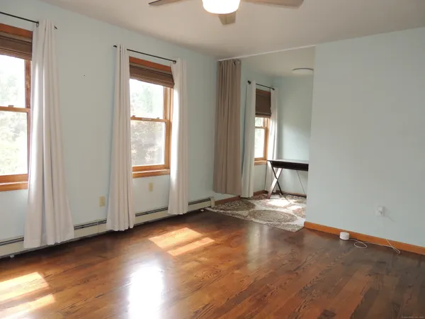 a view of empty room with wooden floor and fan