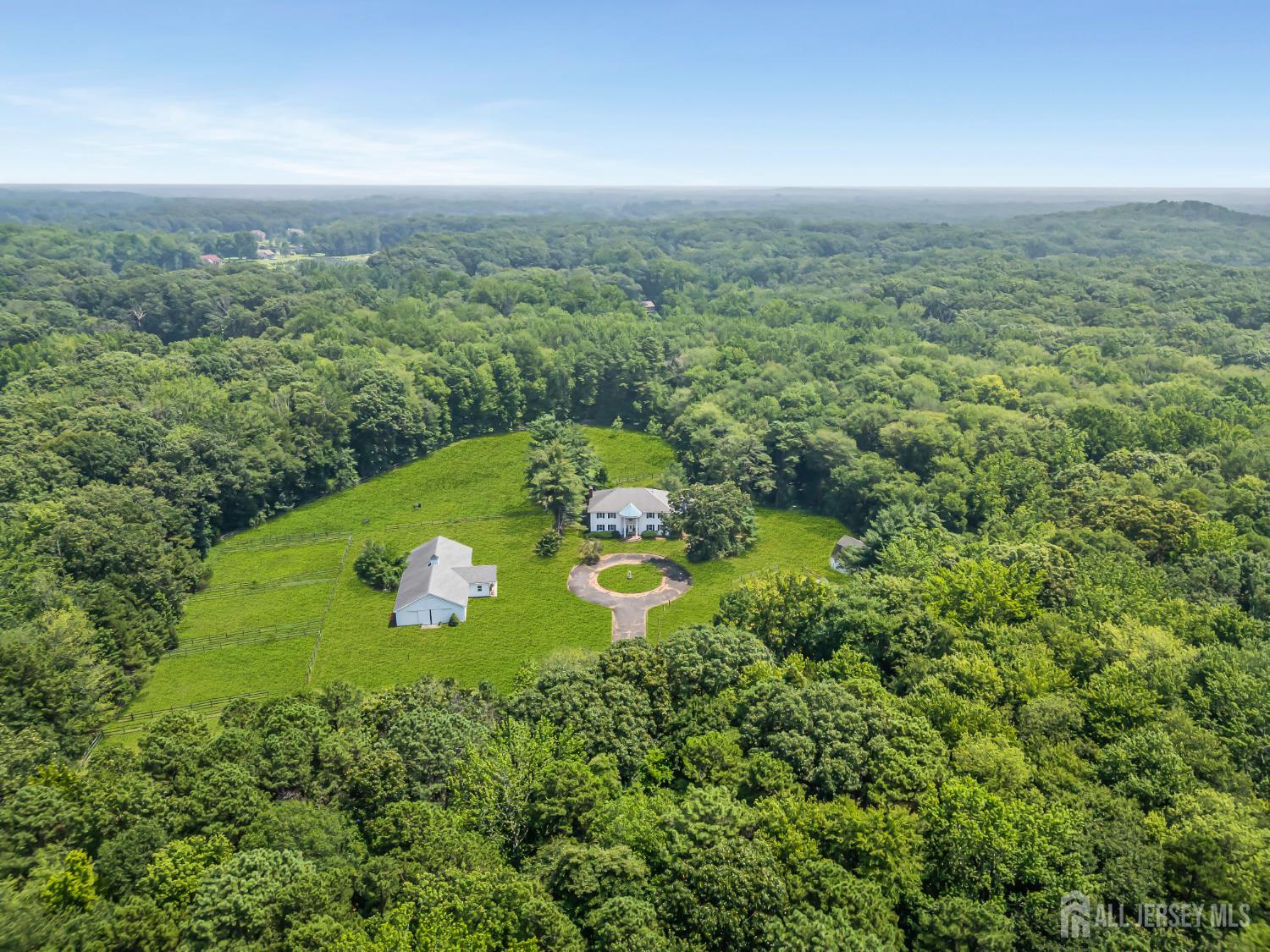 an aerial view of a residential houses with outdoor space and trees all around