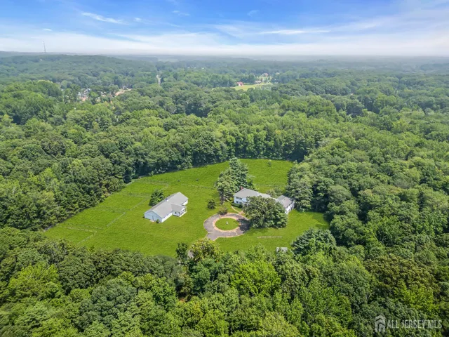 an aerial view of residential houses with outdoor space and trees