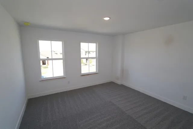 an empty room with windows and ceiling fan