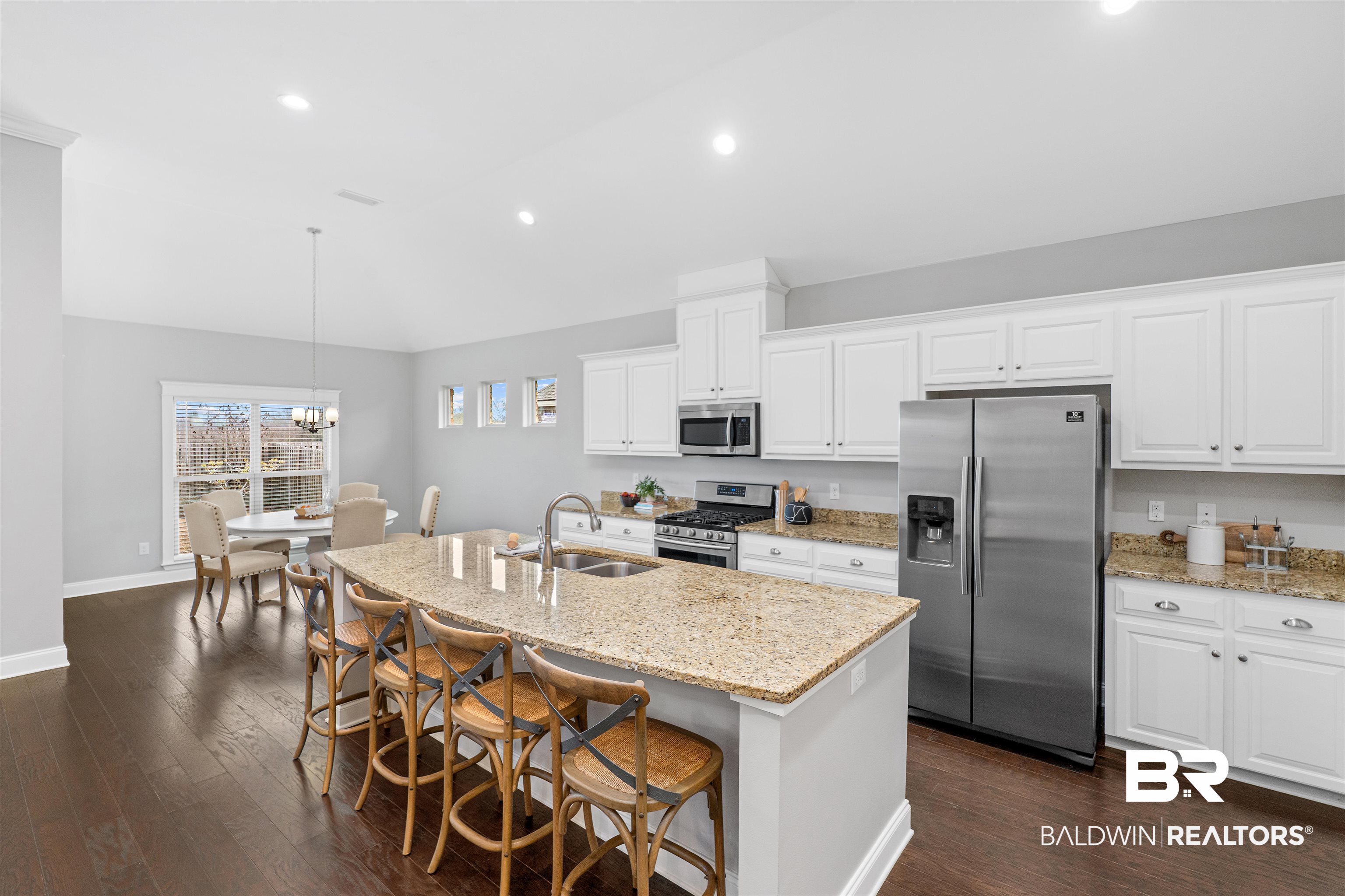 24838 Slater Mill Road Daphne, AL 36526 - Photo 11 of 46 Kitchen featuring stainless steel appliances, light stone counters, a kitchen breakfast bar, decorative light fixtures, and lofted ceiling