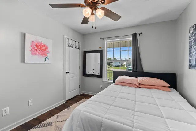 a bedroom with a large bed a flat tv screen and a ceiling fan
