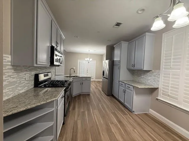 a kitchen with stainless steel appliances granite countertop wooden cabinets a stove top oven a sink and dishwasher