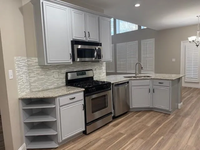 a kitchen with stainless steel appliances granite countertop a sink stove and microwave