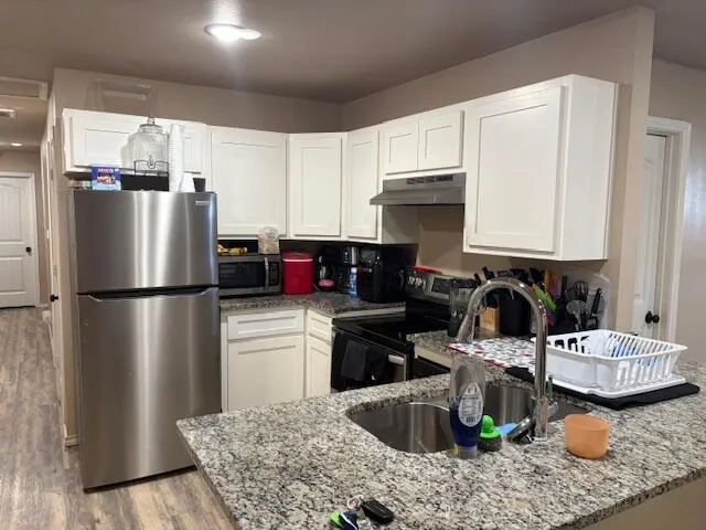 a kitchen with kitchen island a refrigerator a stove a sink and a chairs