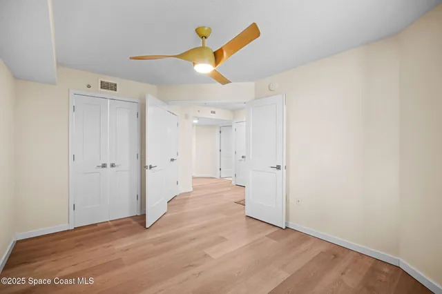 an empty room with windows and ceiling fan
