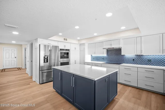 a kitchen with granite countertop white cabinets and stainless steel appliances