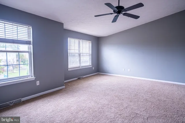 an empty room with windows and fan