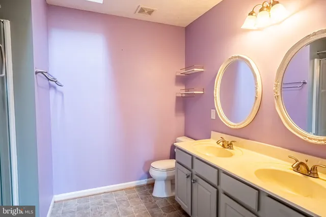 a bathroom with a granite countertop toilet sink and mirror