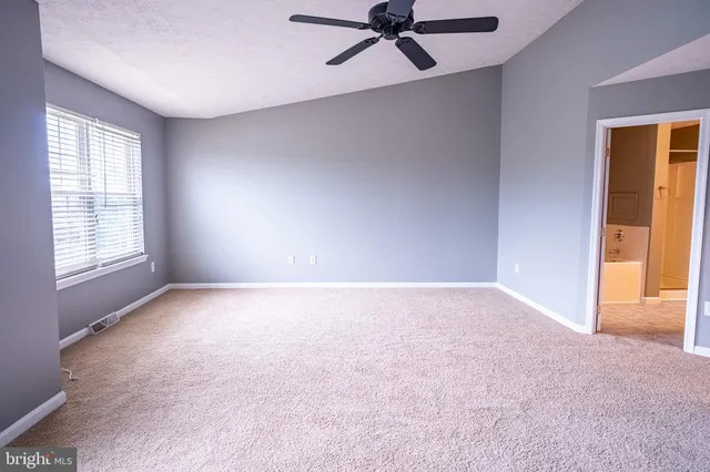 an empty room with a window and a fan