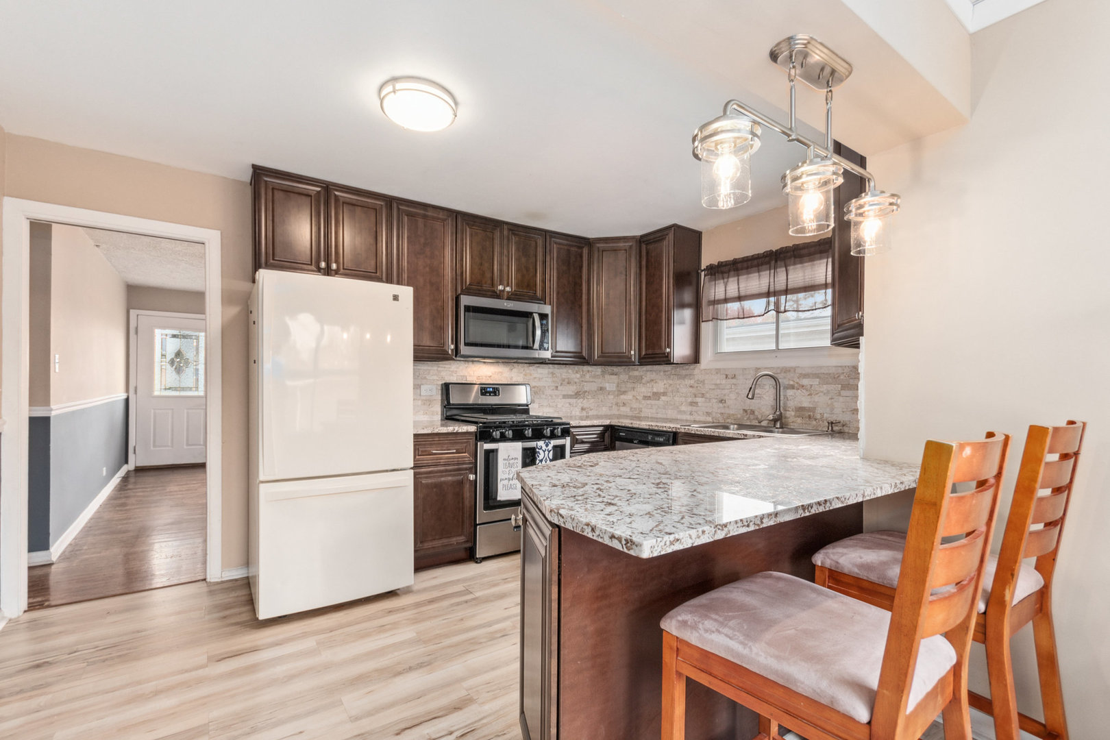 38 Highview Avenue Addison, IL 60101 - Photo 5 of 17 a kitchen with stainless steel appliances granite countertop a refrigerator a sink dishwasher a stove and a dining table with wooden floor