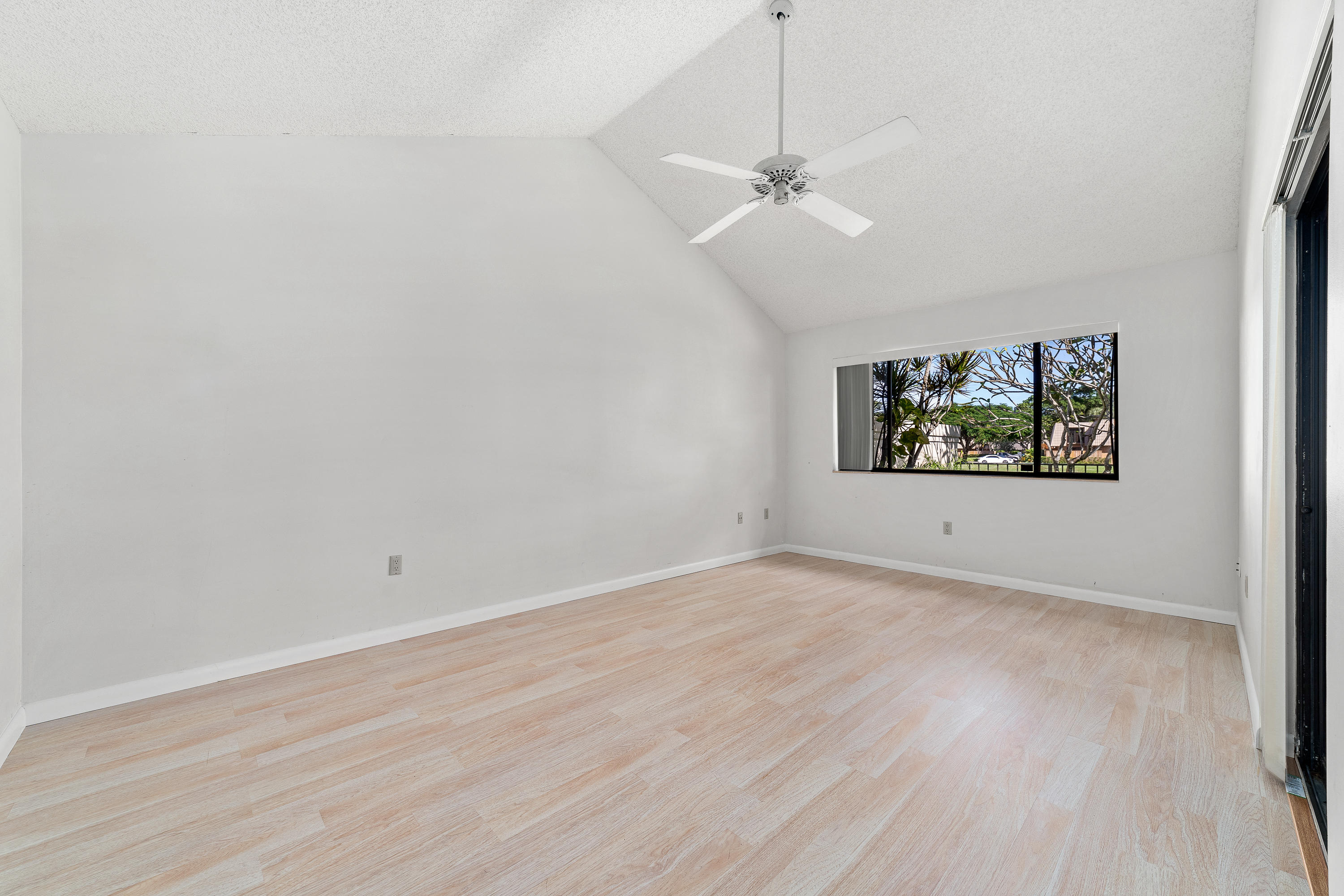 2630 Mohawk Circle West Palm Beach, FL 33409 - Photo 17 of 39 an empty room with wooden floor chandelier fan and windows
