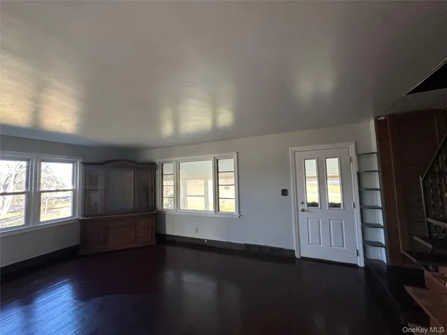 an empty room with wooden floor fireplace and windows