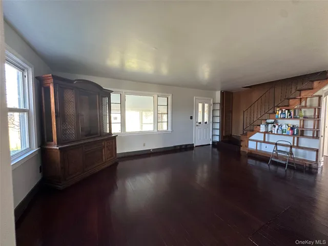 an empty room with wooden floor and windows with curtains