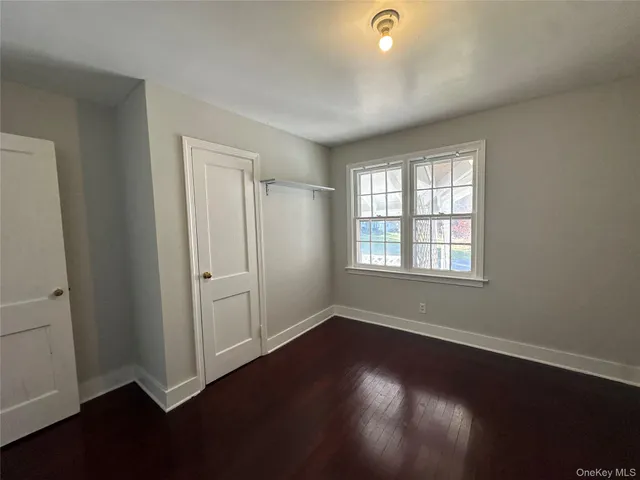 an empty room with wooden floor and windows with curtains