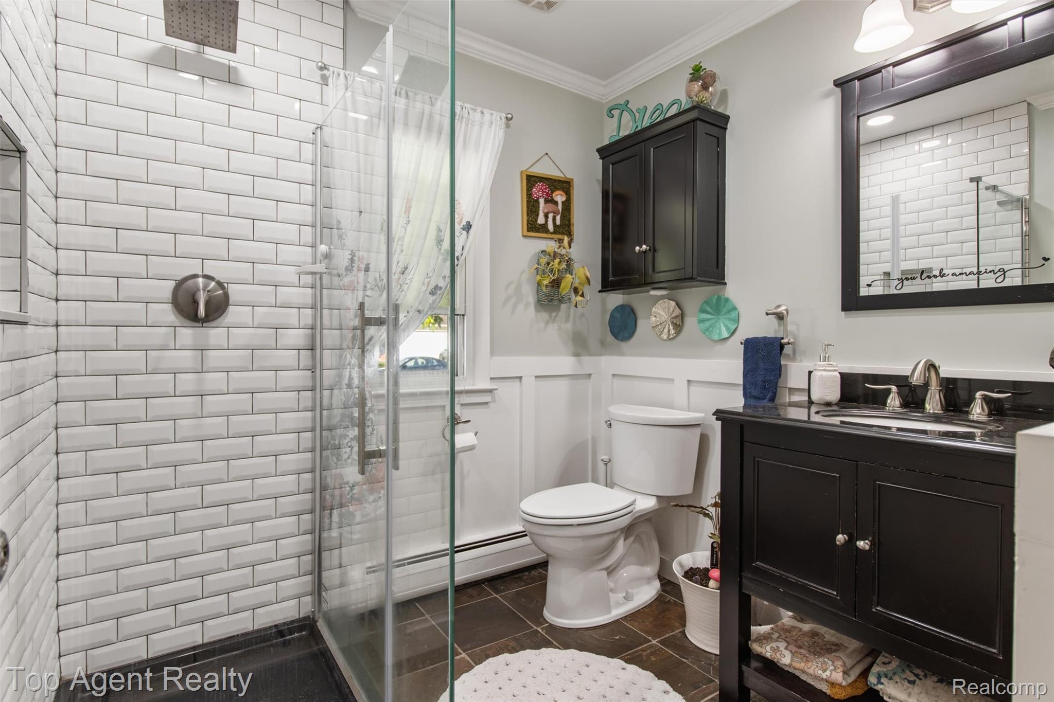 32341 Woody Road Fraser, MI 48026 - Photo 16 of 47 Bathroom featuring a glass-enclosed shower with white subway tile, a dark wood-finish vanity with a dark countertop, a wall-mounted medicine cabinet, and paneling on the lower wall