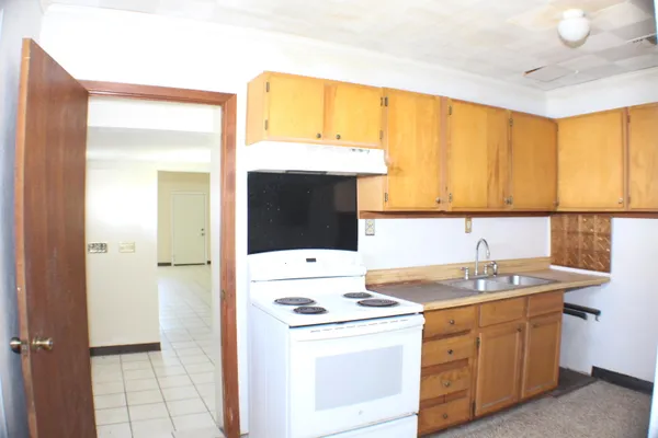 a kitchen with a sink a stove and white cabinets