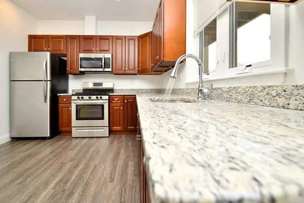 a kitchen with granite countertop a stove a sink and a microwave