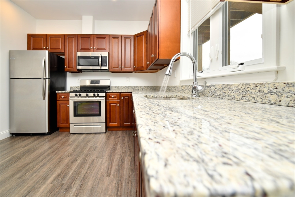 a kitchen with granite countertop a stove a sink and a microwave