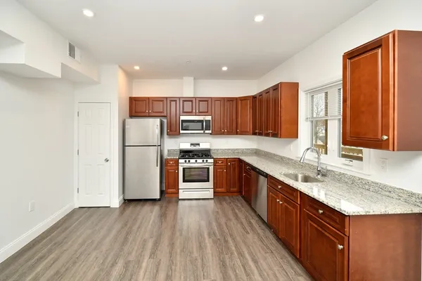 a kitchen with stainless steel appliances granite countertop a refrigerator a sink dishwasher a stove with wooden floors and cabinets