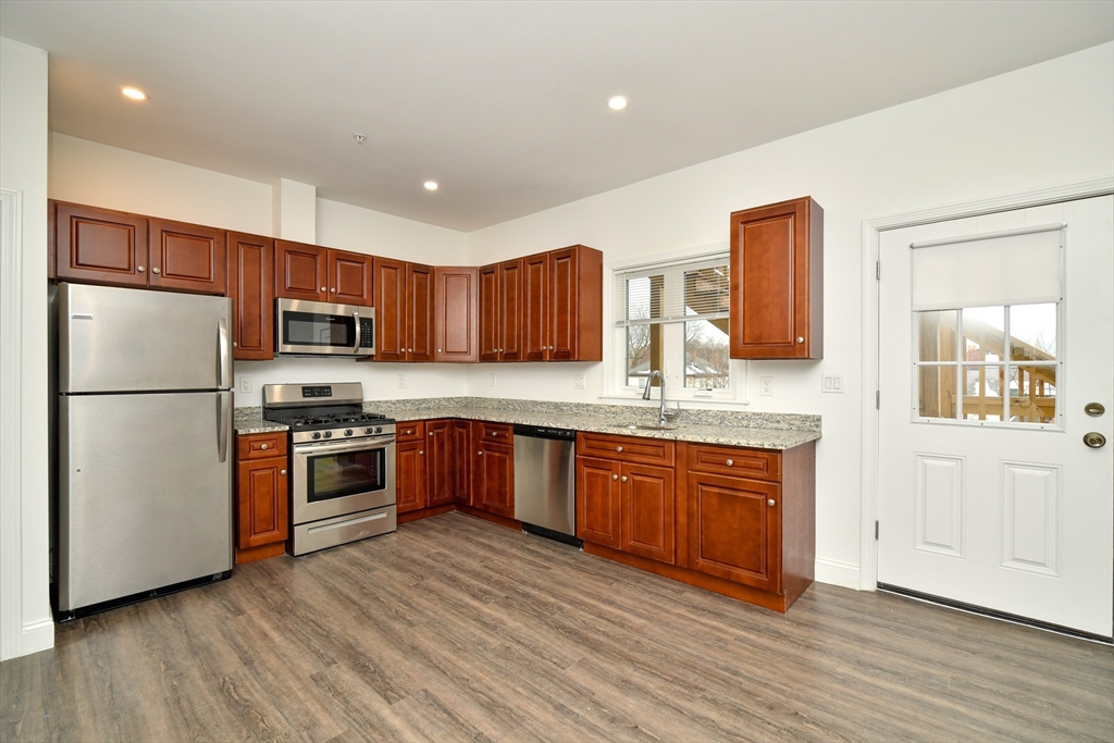 55 Dale Street, Unit 3 Boston, MA 02119 - Photo 5 of 24 a kitchen with stainless steel appliances granite countertop a refrigerator a sink dishwasher a stove with wooden cabinets and floor