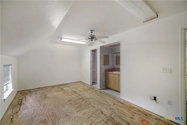 an empty room with a chandelier fan and entryway
