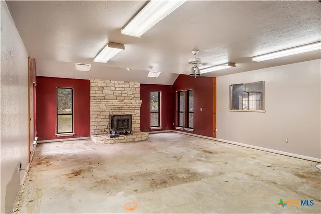 an empty room with windows and fireplace