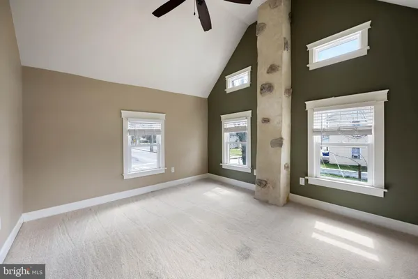 an empty room with windows and ceiling fan