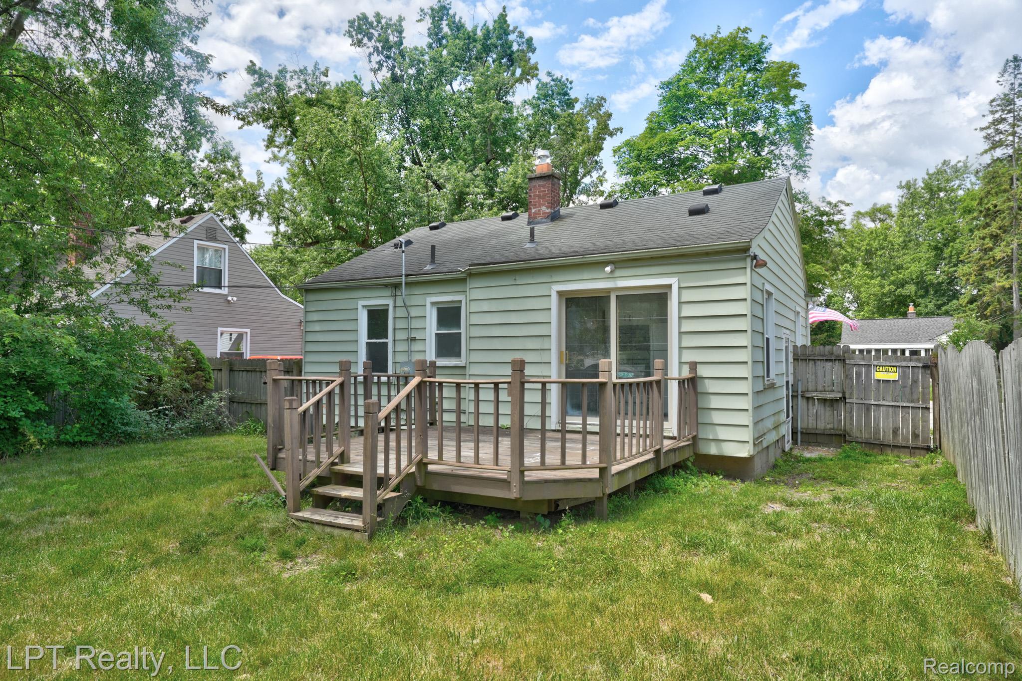 23038 Violet Street Farmington, MI 48336 - Photo 26 of 29 Rear exterior featuring a wooden deck with railing and steps, light green siding, and a sliding glass door