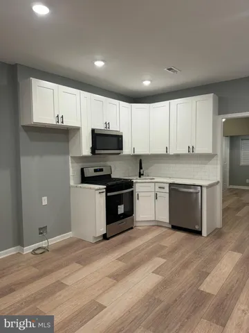 a kitchen with granite countertop white cabinets and stainless steel appliances