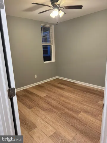 an empty room with wooden floor and fan