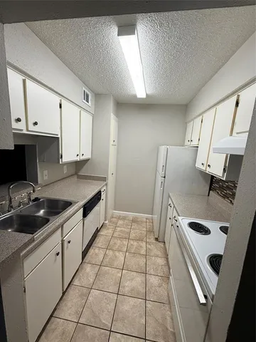 a kitchen with granite countertop a sink a stove a refrigerator and cabinets