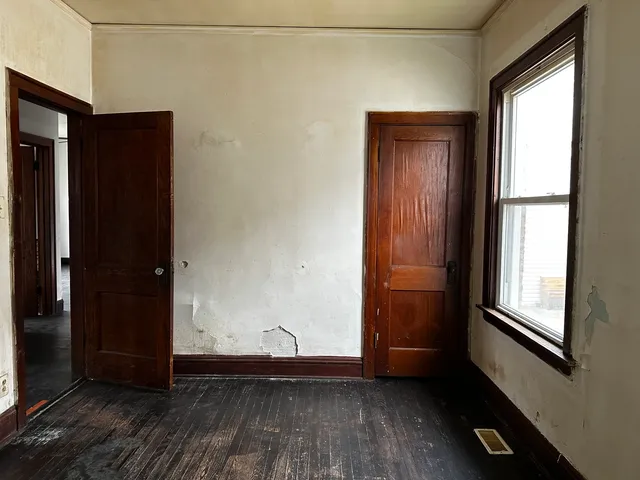 an empty room with wooden floor and windows