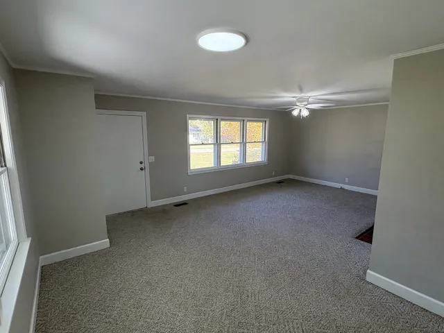an empty room with windows fireplace and fans