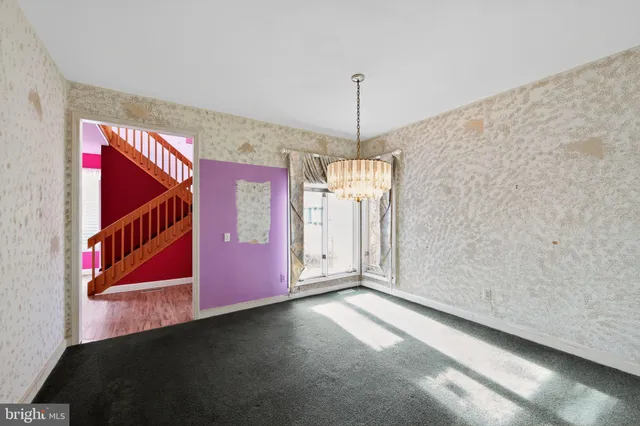 a view of an empty room with chandelier fan