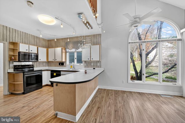 a kitchen with stainless steel appliances granite countertop a sink a stove and a wooden floors